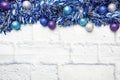 Christmas frame made of Christmas garland tinsel decorations in silver and blue on a light brick background. Copy space. Flat lay Royalty Free Stock Photo