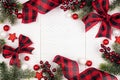 Christmas frame of ornaments, branches and red and black checked buffalo plaid ribbon, top view on a white wood background Royalty Free Stock Photo