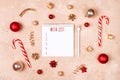 Christmas frame with red, golden holiday decorations and notebook with wish list. New year planning concept. Flat lay