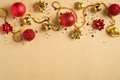 Christmas frame top border made of golden decorations, ribbon and red balls over yellow background. Flat lay, top view. Xmas Royalty Free Stock Photo