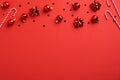 Christmas frame top border made of red baubles decoration, tinsel, candy canes, confetti on red background. Flat lay, top view. Royalty Free Stock Photo