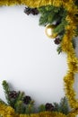 Christmas frame vertical, with festive decorations such as gold tinsel, baubles, conifer tree branches and cones. Copy space for