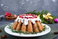 Christmas fruit cake on white plate. Homemade fruitcake decorated with rosemary, powdered sugar and lingonberry on a wooden rustic Royalty Free Stock Photo