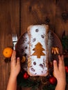 Christmas fruitcake in child hands powdered sugar tangerine cranberry fir tree festive decoration wooden table flat lay