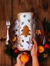 Christmas fruitcake in child hands powdered sugar tangerine cranberry fir tree festive decoration wooden table flat lay