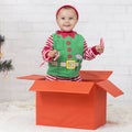 Adorable Santa helper with lollipops standing in big gift box