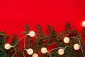 Christmas garland on branches of spruce on red background. round lights decorate Christmas tree. Concept of blank frame, copy