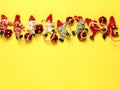 Christmas garland of colorful knitted toys in the form of men and red balls laid out in a line on a bright yellow background. Royalty Free Stock Photo