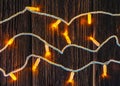 Christmas garland with yellow led and white wire on dark wood board