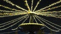 A Christmas garland with yellow lights and flags swings in the wind during a snowfall