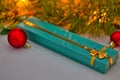 Christmas gift in a blue box with gold ribbon lies under the Christmas tree. red Christmas balls and a beautiful spruce Royalty Free Stock Photo