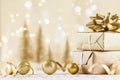 Christmas Gift Box Against Golden Bokeh Background. Holiday Greeting Card.