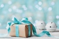 Christmas gift box and jingle bell against turquoise bokeh background. Holiday greeting card. Royalty Free Stock Photo