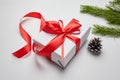 Christmas gift box with red ribbon and green pine tree branch with cones on white Royalty Free Stock Photo