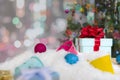 Christmas gift box on snow floor and decorated Christmas tree with blurred abstract bokeh glitter background Royalty Free Stock Photo