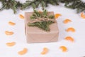 Christmas gift box on a white wooden backgroundChristmas gift box on a white wooden background. Frame of fir branches, tangerine