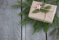 Christmas gift box on wooden table, handicraft wrapping, parchment, twine, fir tree twigs, cute simple last minute present handmad