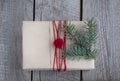 Christmas gift box on wooden table, handicraft wrapping, parchment, twine, fir tree twigs, cute simple last minute present handmad