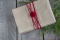 Christmas gift box on wooden table, handicraft wrapping, parchment, twine, fir tree twigs, cute simple last minute present handmad