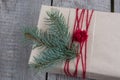 Christmas gift box on wooden table, handicraft wrapping, parchment, twine, fir tree twigs, cute simple last minute present handmad