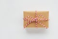 Christmas gift box wrapped in craft paper with red and white striped twine bow on white background. Top view, flat lay, copy space Royalty Free Stock Photo