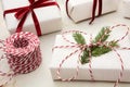 Christmas gift box wrapped in white craft paper and decorative red rope ribbon on marmoreal surface. Close up.