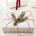 Christmas gift box wrapped in white craft paper and decorative red rope ribbon on marmoreal surface. Close up.