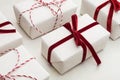 Christmas gift box wrapped in white paper and decorative red rope ribbon on marmoreal surface. Isometric. Close up. Royalty Free Stock Photo