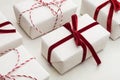 Christmas gift box wrapped in white paper and decorative red rope ribbon on marmoreal surface. Isometric. Close up