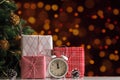 Christmas gift boxes and alarm clock on blurred background of New Year lights Royalty Free Stock Photo