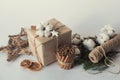 Christmas gift boxes with flowers and decorative objects Eco cotton, cinnamon, spruce branches and jute rope hank over white backg