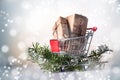 Christmas gift boxes in kraft paper in a shopping cart or trolley on fir branches, snowy bokeh light background, copy space