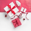 Christmas gift boxes with red ribbon, decoration, pine cones on white and red paper background. Royalty Free Stock Photo