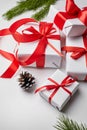 Christmas gift boxes with red ribbon and green pine tree branch with cones on white Royalty Free Stock Photo