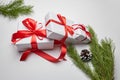 Christmas gift boxes with red ribbon and green pine tree branch with cones on white Royalty Free Stock Photo