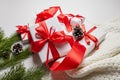 Christmas gift boxes with red ribbon and knitted sweater with green pine tree branch and cones on white Royalty Free Stock Photo
