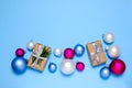 Christmas gift boxes with silver ribbon bow surrounded with Christmas balls. Christmas gifts on a blue background. Pastel colors. Royalty Free Stock Photo