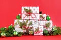 Christmas gift boxes on a red background, decorated of fir branches, pine cones and shiny green Christmas decorations. Royalty Free Stock Photo