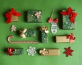 Christmas gift composition. Flat lay green and red winter decorations presents on green background with gold detail.