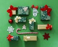 Christmas gift composition. Flat lay green and red winter decorations presents on green background with gold detail.