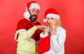 Christmas gift concept. Couple cheerful face check out gift in christmas sock. Woman and bearded man in santa hat Royalty Free Stock Photo