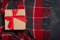 Christmas gift craft box with a red bow on a red and black checkered plaid on a black background Royalty Free Stock Photo