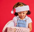 Christmas, gift and girl child surprise, wow and curious in studio, happy and shock against red background. Box, present