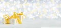 Christmas gift with a gold bow on a sparkling bokeh background. Copy space for text Royalty Free Stock Photo