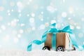 Christmas gift or present box on wheels against turquoise bokeh background. Holiday greeting card. Royalty Free Stock Photo
