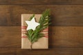 Christmas gift present with recycled wrapping paper and natural evergreen decorations on wood background