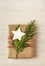 Christmas gift present with recycled wrapping paper and natural decorations on rustic wood background