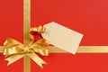 Christmas gift red background, gold ribbon bow, gift tag, copy space Royalty Free Stock Photo