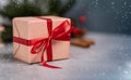 Christmas gift with red bow on gray table on background with blurred light. Close up. Christmas composition with copy space Royalty Free Stock Photo