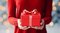 Christmas gift in a red box in gentle female hands on a light, New Year& x27;s background with bokeh and copy space Royalty Free Stock Photo